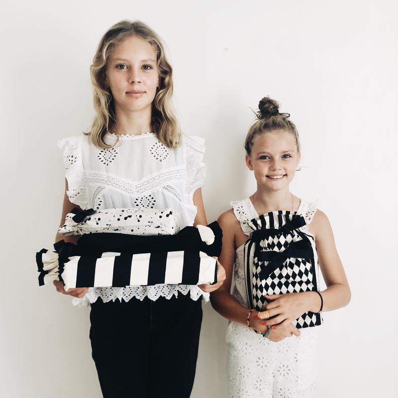 Deux filles tenant des sacs-cadeaux réutilisables de différents modèles.