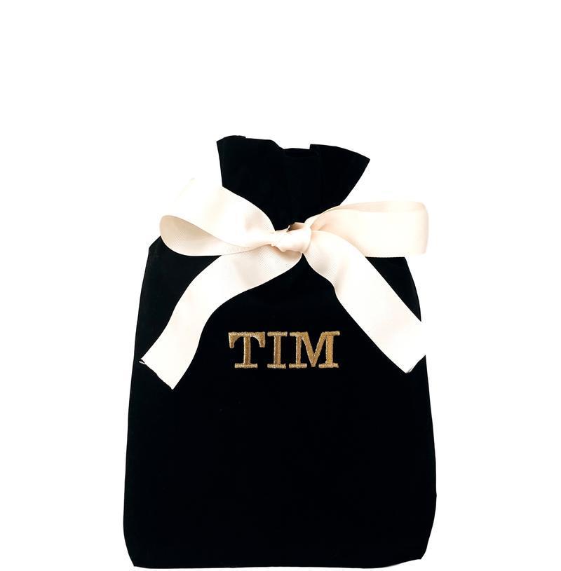 
                                      
                                        Un sac cadeau réutilisable noir avec "TIM" imprimé sur le devant.
                                      
                                    