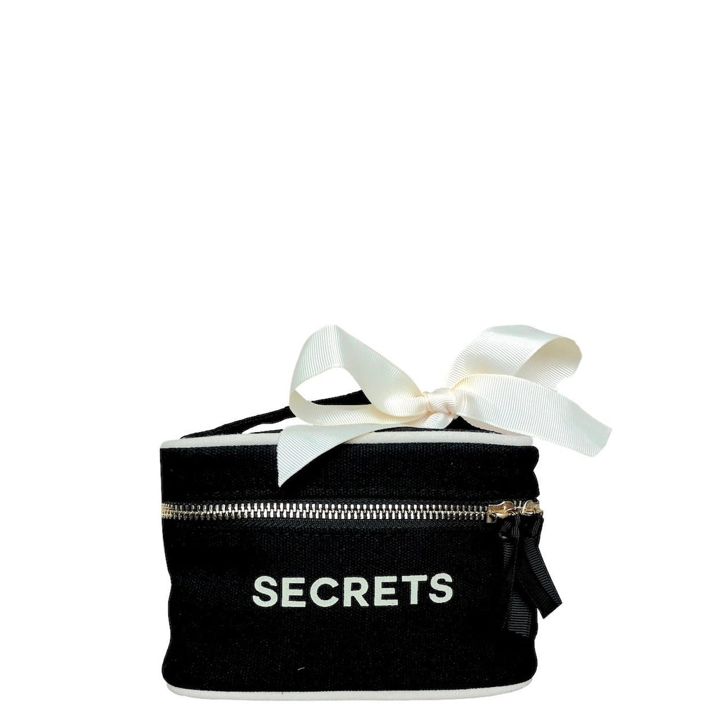 
                                      
                                        Mini boîte de beauté noire avec "secrets" sur le devant et un nœud blanc sur la poignée.
                                      
                                    