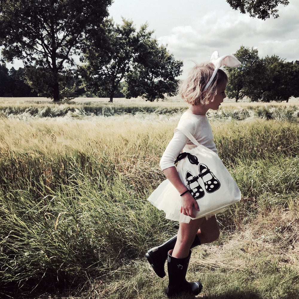 Un enfant dans un champ herbeux avec un sac à chaussures.